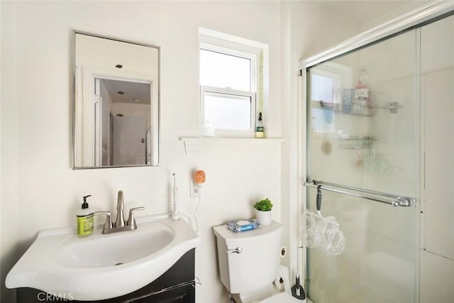 bathroom featuring a shower with shower door, toilet, and vanity