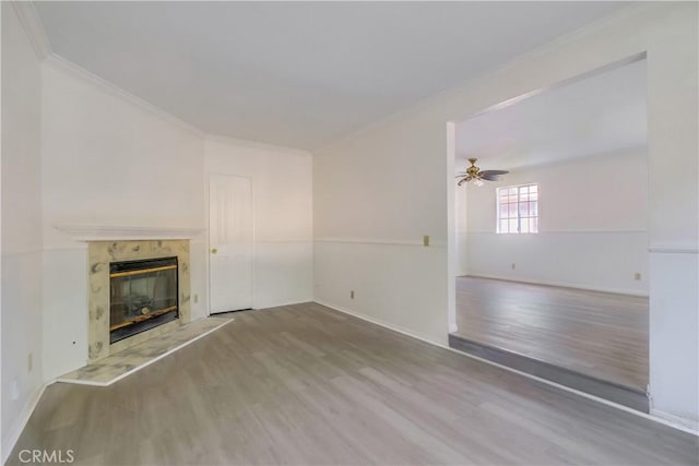 unfurnished living room featuring light wood-type flooring, ceiling fan, ornamental molding, and a fireplace