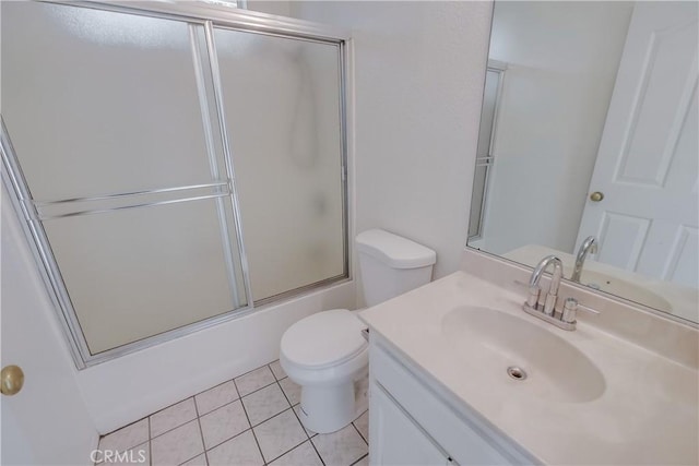 full bathroom with combined bath / shower with glass door, vanity, tile patterned floors, and toilet