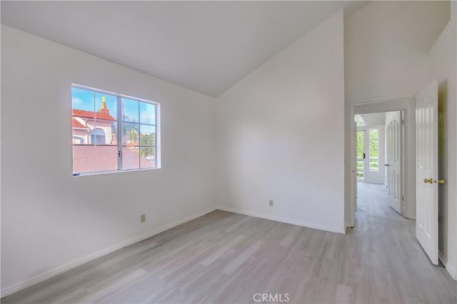 empty room featuring light wood-type flooring and vaulted ceiling