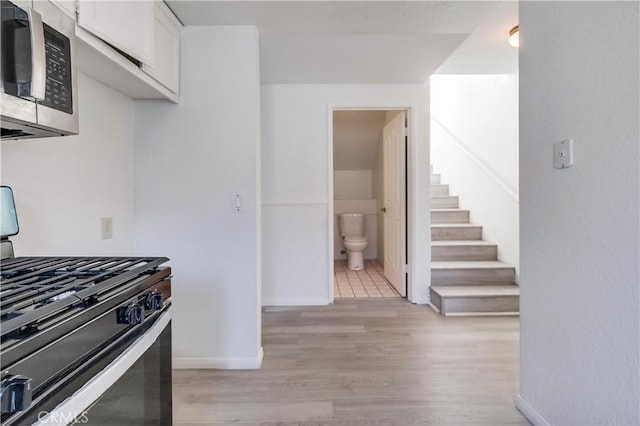 kitchen featuring range with gas cooktop, white cabinetry, and light hardwood / wood-style flooring