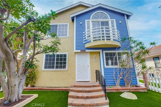 view of front of home featuring a front lawn and a balcony