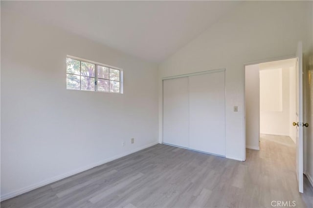 unfurnished bedroom with a closet, lofted ceiling, and light hardwood / wood-style flooring