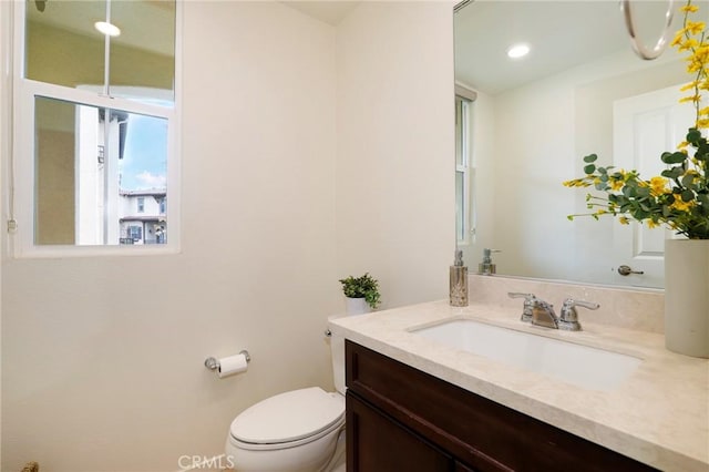 bathroom featuring toilet, a wealth of natural light, and vanity