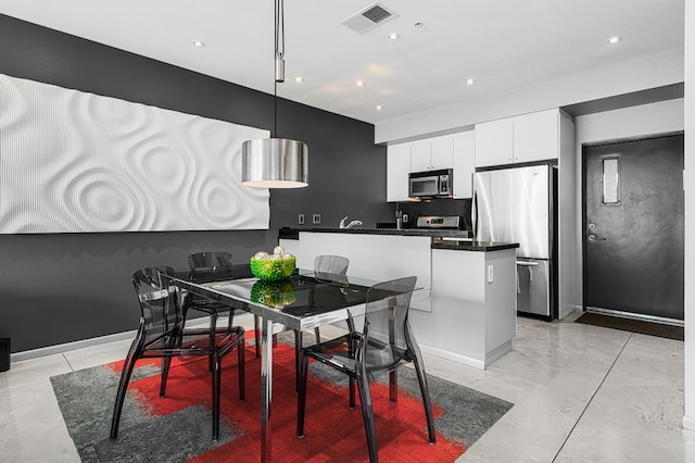 interior space featuring appliances with stainless steel finishes, backsplash, hanging light fixtures, a kitchen island, and white cabinets