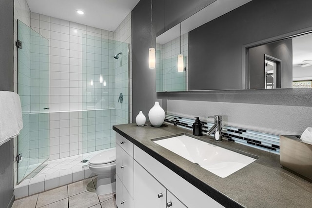 bathroom featuring toilet, vanity, tile patterned floors, and a tile shower