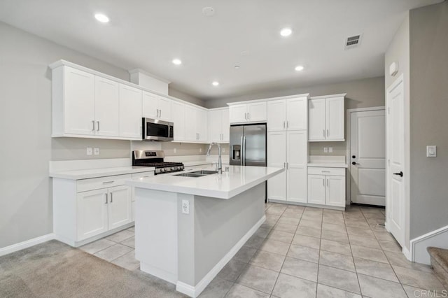 kitchen featuring a center island with sink, sink, light tile patterned flooring, stainless steel appliances, and white cabinets