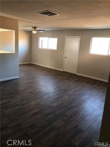 unfurnished room with dark wood-type flooring and ceiling fan