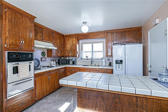 kitchen with tile counters, kitchen peninsula, sink, and white appliances