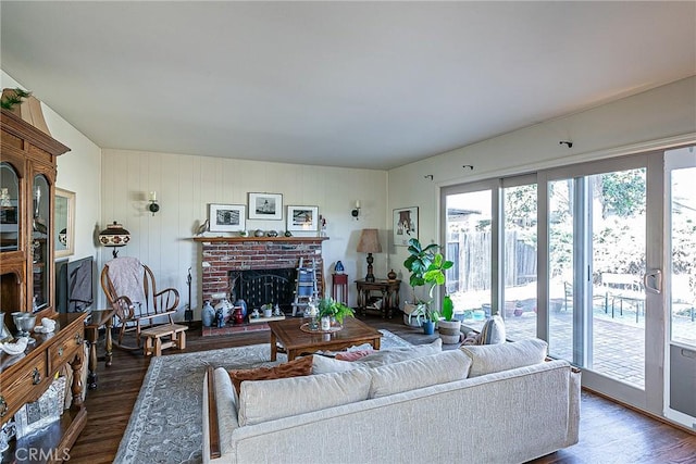 living room featuring a brick fireplace and dark wood-type flooring