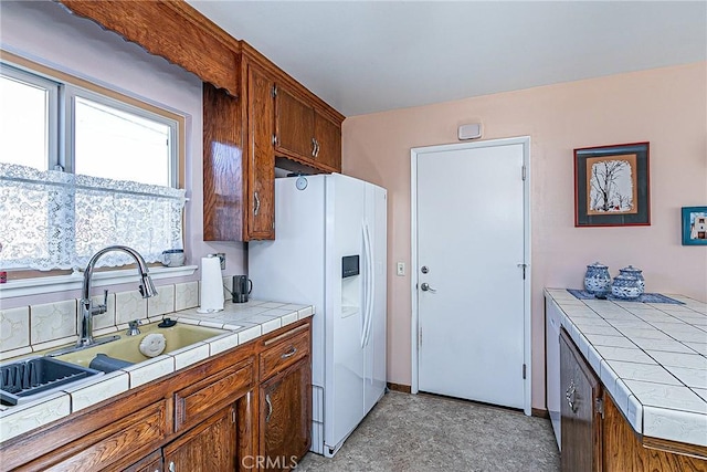 kitchen with sink, white refrigerator with ice dispenser, and tile counters