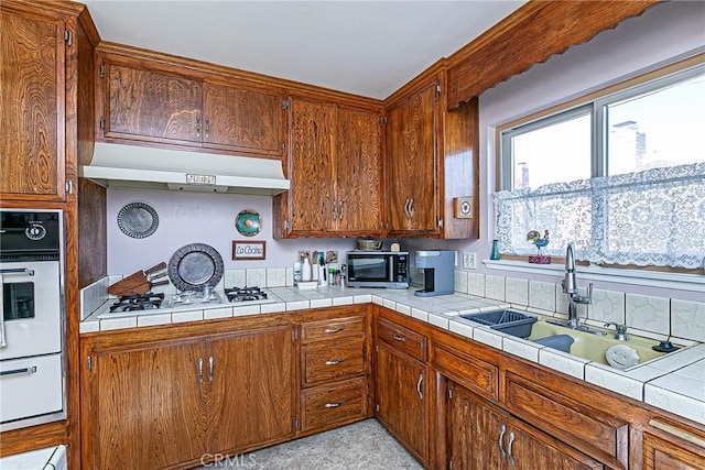 kitchen featuring oven, tile counters, and sink