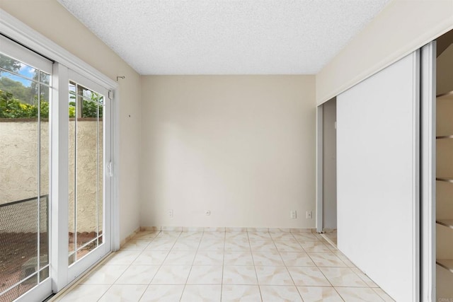 unfurnished room with light tile patterned floors and a textured ceiling