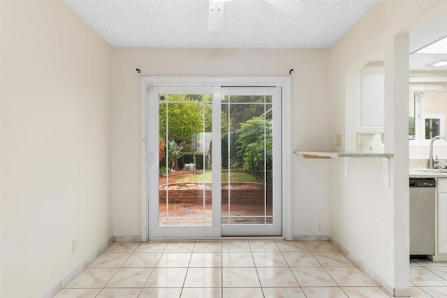 interior space featuring light tile patterned flooring, plenty of natural light, sink, and a textured ceiling