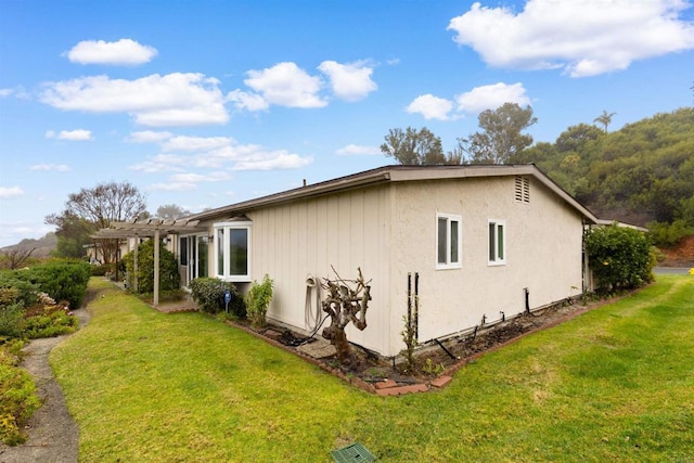 view of property exterior featuring a pergola and a lawn