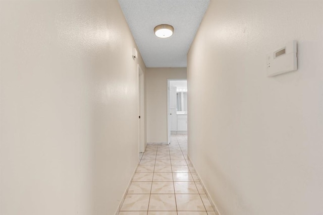 hall featuring light tile patterned floors and a textured ceiling