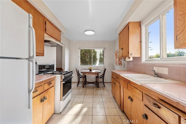 kitchen featuring backsplash, sink, white appliances, tile counters, and light tile patterned floors