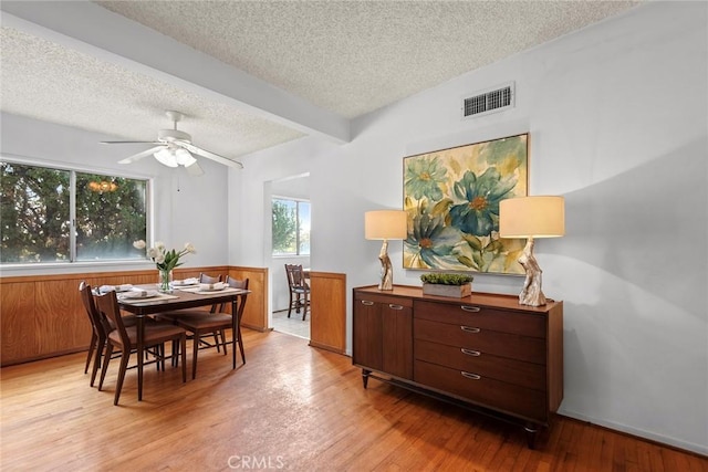 dining room featuring ceiling fan, beamed ceiling, a textured ceiling, and light hardwood / wood-style floors