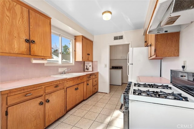 kitchen with white appliances, washer / clothes dryer, tasteful backsplash, sink, and range hood