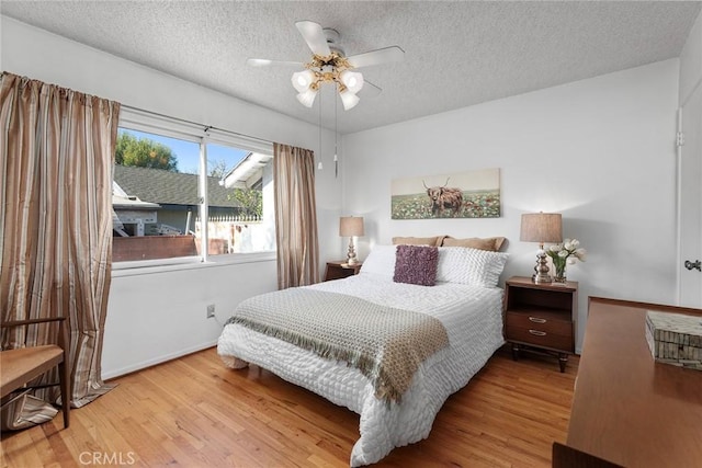 bedroom with ceiling fan, a textured ceiling, and light hardwood / wood-style flooring