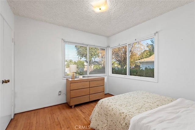 bedroom with light wood-type flooring and a textured ceiling