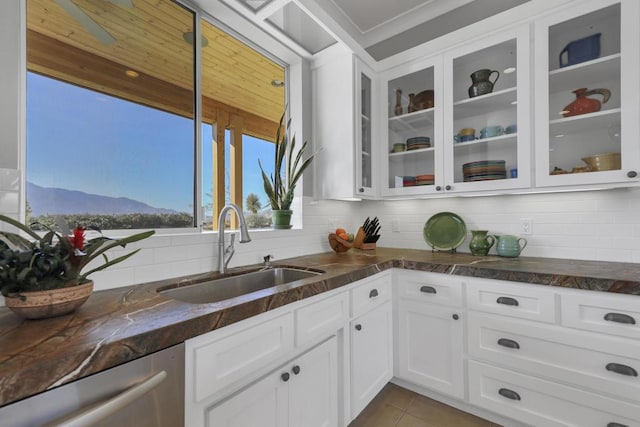 kitchen with sink, white cabinets, decorative backsplash, stainless steel dishwasher, and a mountain view