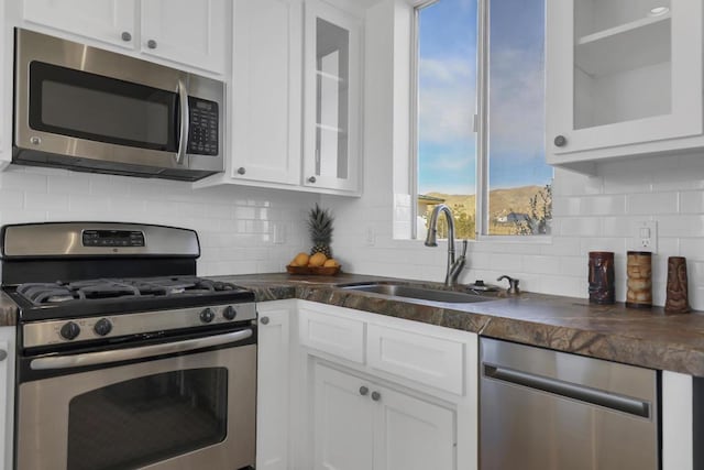 kitchen with sink, decorative backsplash, white cabinets, and appliances with stainless steel finishes