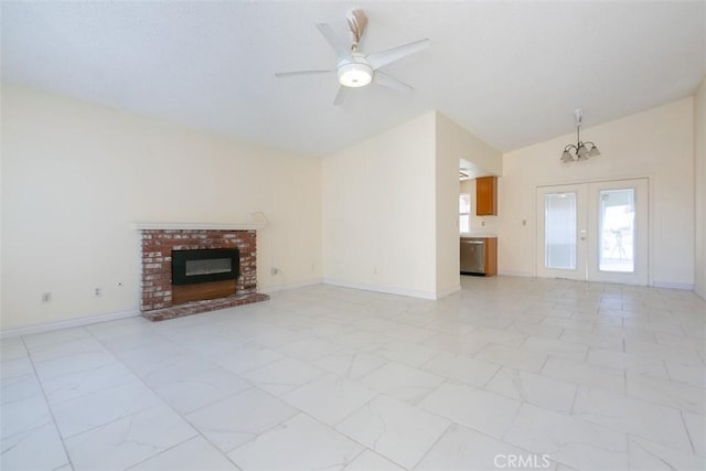 unfurnished living room featuring lofted ceiling, french doors, a fireplace, and ceiling fan with notable chandelier