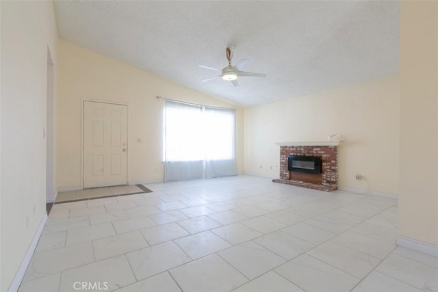 unfurnished living room with a textured ceiling, a ceiling fan, baseboards, vaulted ceiling, and a brick fireplace