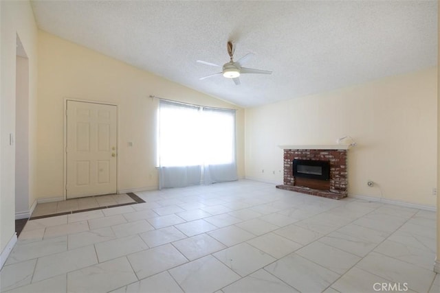 unfurnished living room with lofted ceiling, ceiling fan, a brick fireplace, and a textured ceiling