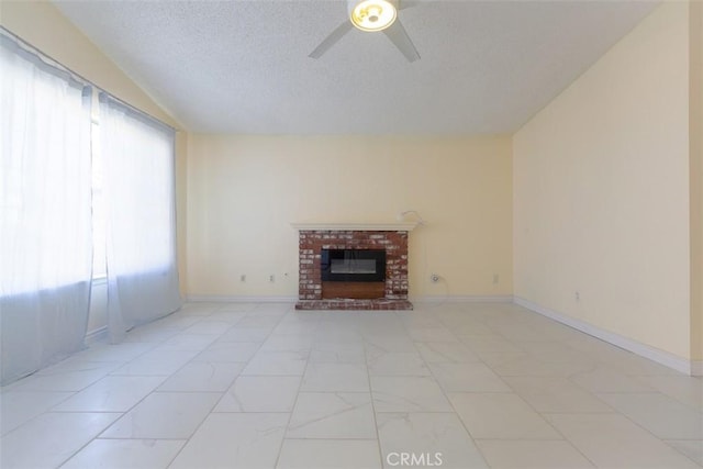 unfurnished living room with ceiling fan, a brick fireplace, and a textured ceiling