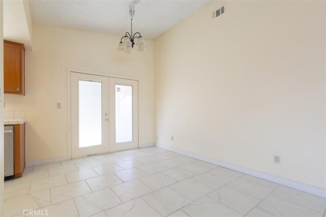 unfurnished dining area with french doors and a notable chandelier