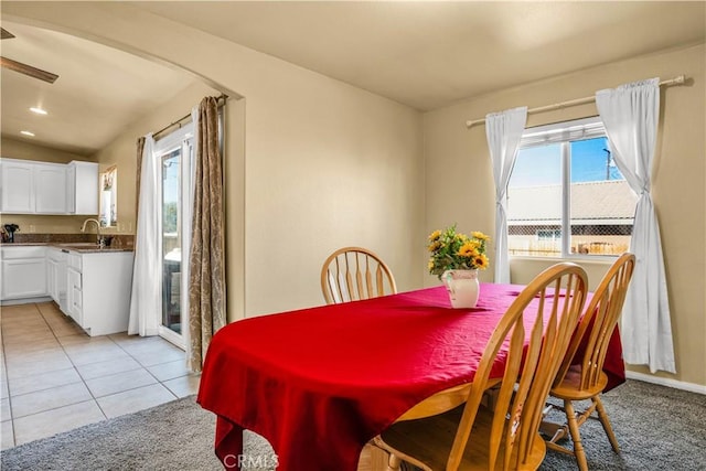 dining space featuring a healthy amount of sunlight, vaulted ceiling, sink, and light tile patterned floors