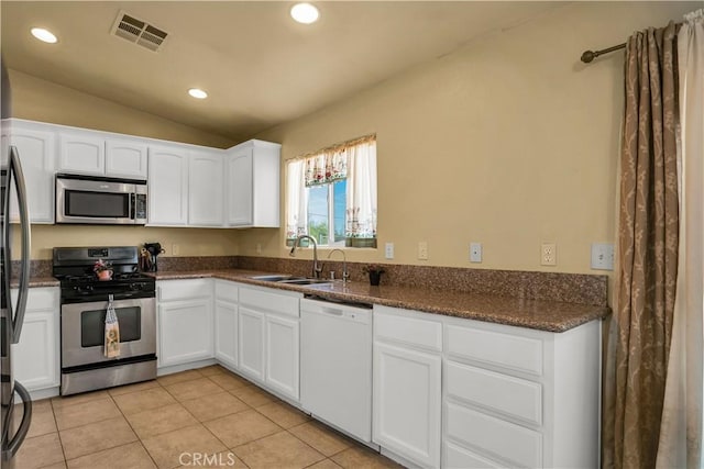 kitchen with vaulted ceiling, appliances with stainless steel finishes, white cabinets, and sink