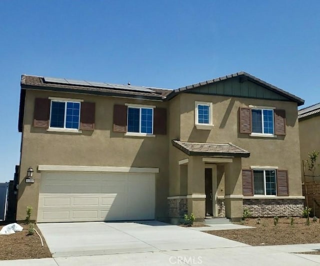 view of front of home featuring stone siding, roof mounted solar panels, and stucco siding