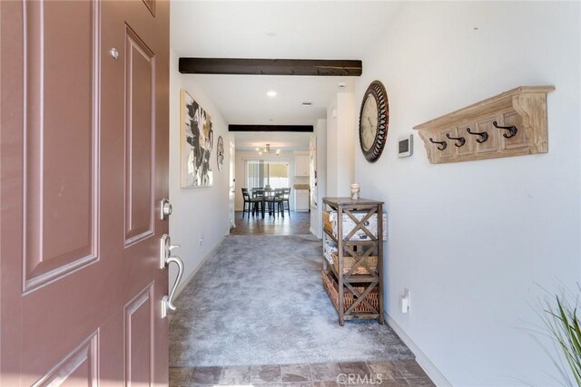 carpeted entryway featuring beamed ceiling