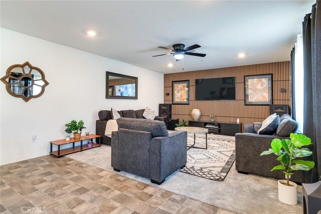 living room featuring ceiling fan and wooden walls