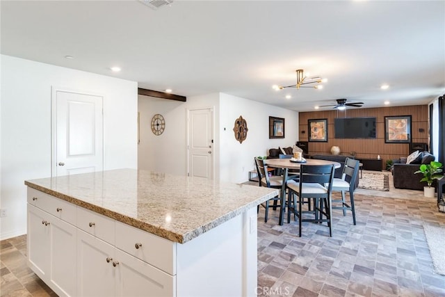 kitchen featuring open floor plan, a center island, light stone countertops, white cabinetry, and recessed lighting