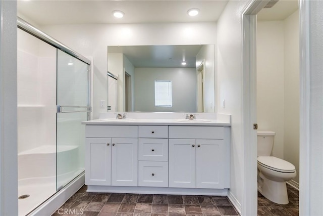 full bathroom with toilet, a shower stall, double vanity, and a sink