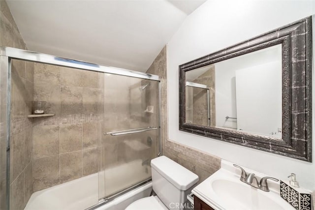 full bathroom featuring toilet, vanity, shower / bath combination with glass door, and lofted ceiling