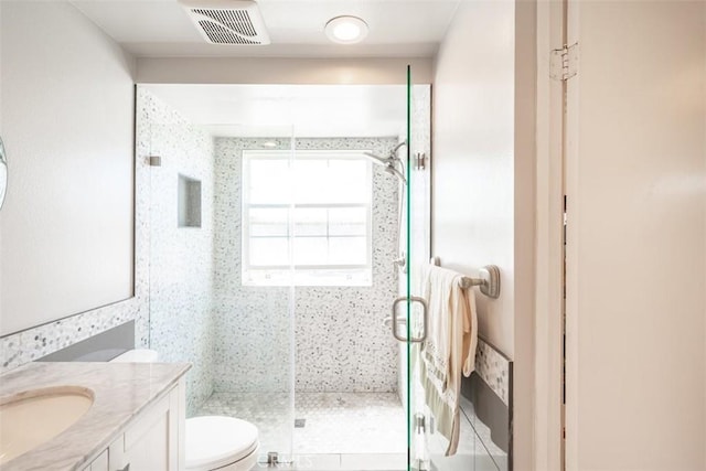 bathroom featuring an enclosed shower, vanity, and toilet