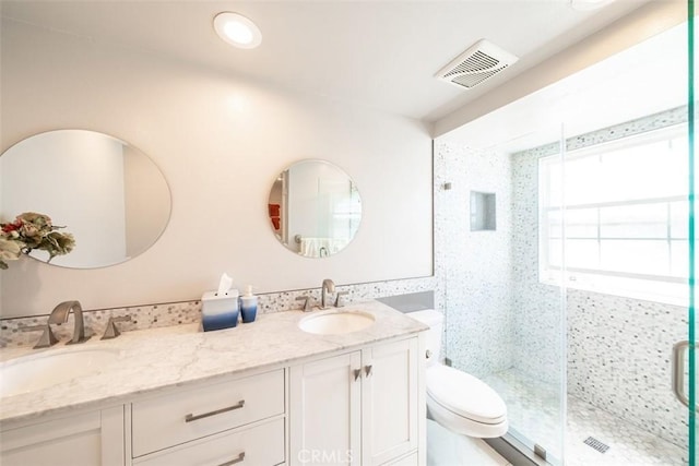 bathroom featuring a shower with shower door, vanity, and toilet