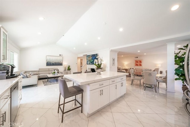 kitchen with a kitchen island, white cabinetry, a kitchen breakfast bar, vaulted ceiling, and stainless steel dishwasher