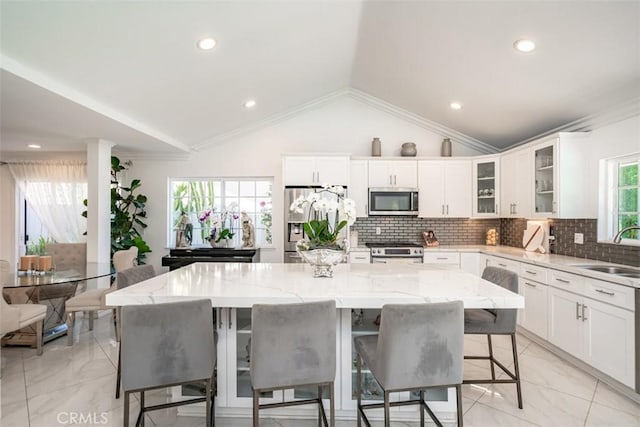 kitchen with lofted ceiling, a center island, and stainless steel appliances