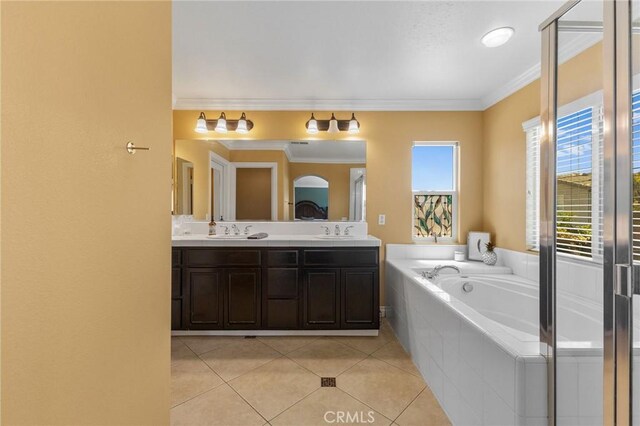 bathroom featuring tiled tub, vanity, ornamental molding, and tile patterned flooring