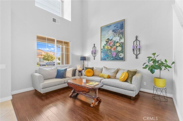 living room with a wealth of natural light, hardwood / wood-style floors, and a towering ceiling