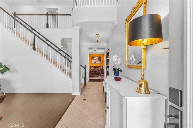 foyer entrance with ornate columns, light tile patterned floors, and crown molding