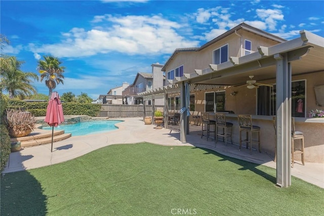 back of house featuring a lawn, ceiling fan, a patio area, a fenced in pool, and an outdoor bar