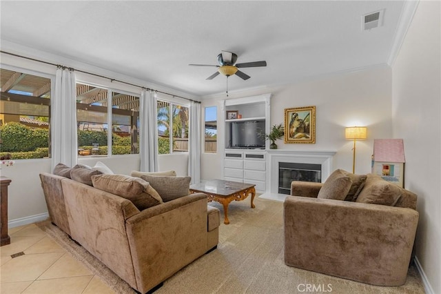 living room featuring light tile patterned floors, ceiling fan, ornamental molding, and built in features