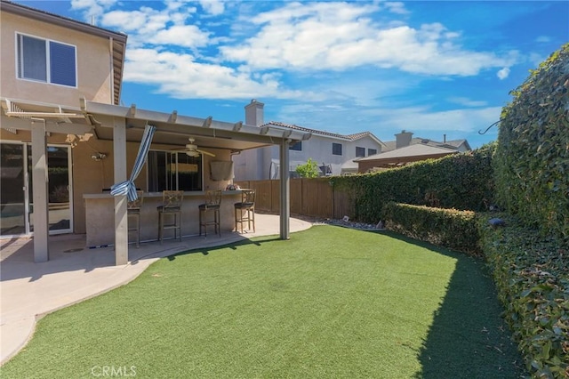 view of yard featuring ceiling fan, a patio, and an outdoor bar